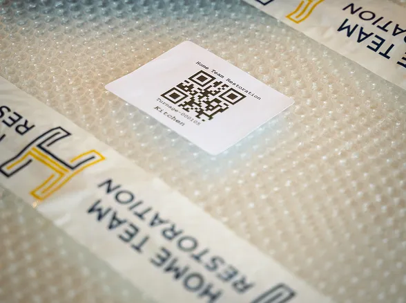 Home Team Restoration barcode label on bubble-wrapped item for pack-out inventory tracking in Goldsboro, NC
