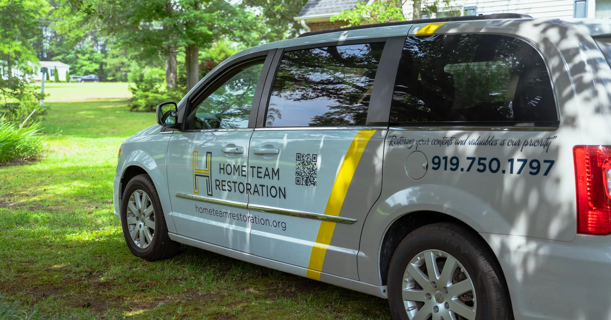 White van with Home Team Restoration branding, a QR code, and contact number 919.750.1797.