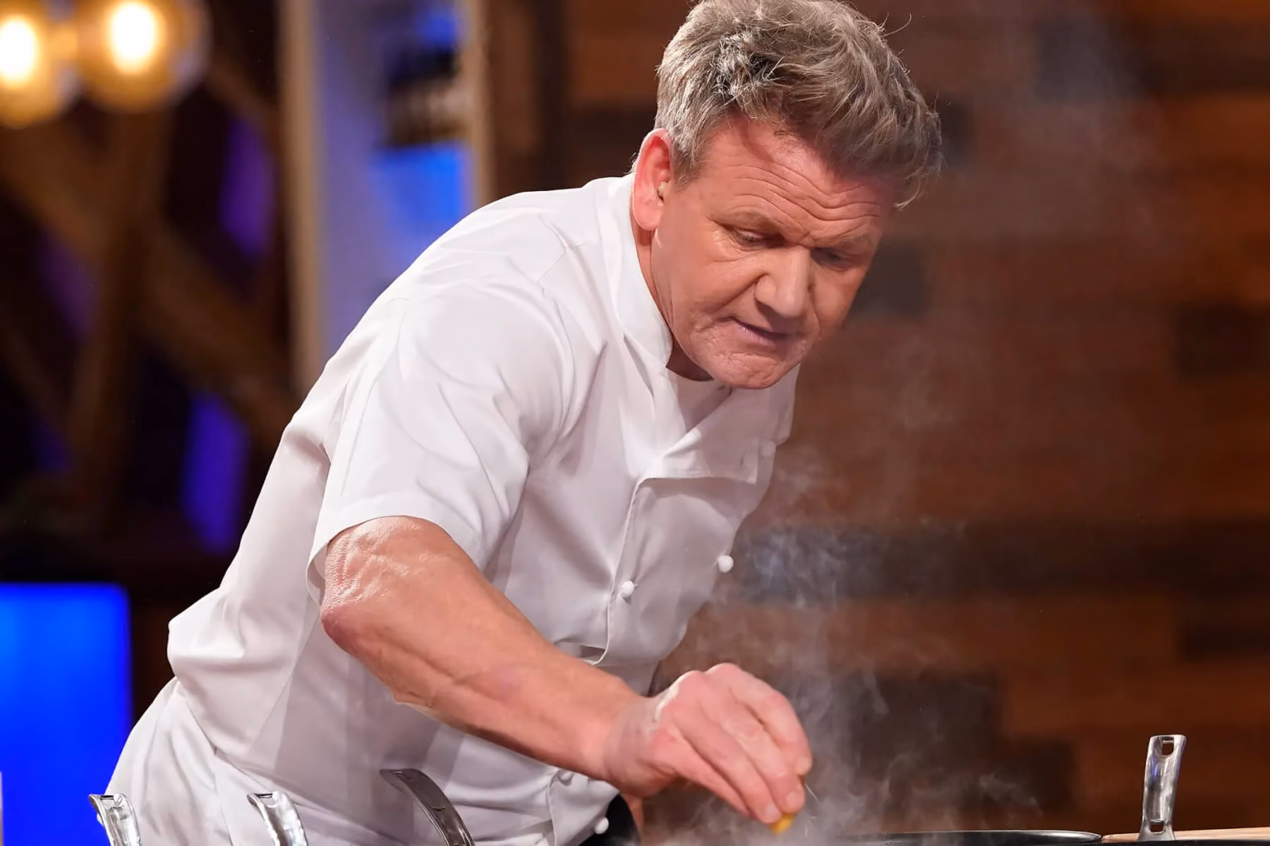 Chef in whites seasons a dish in the kitchen