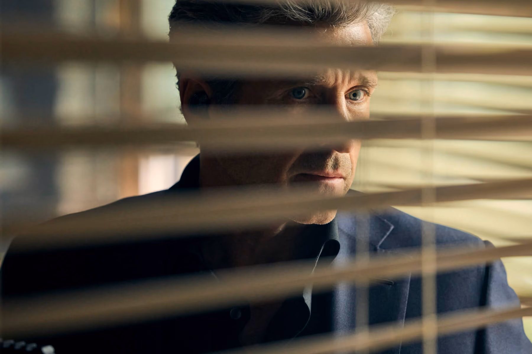 Man peers through window blinds