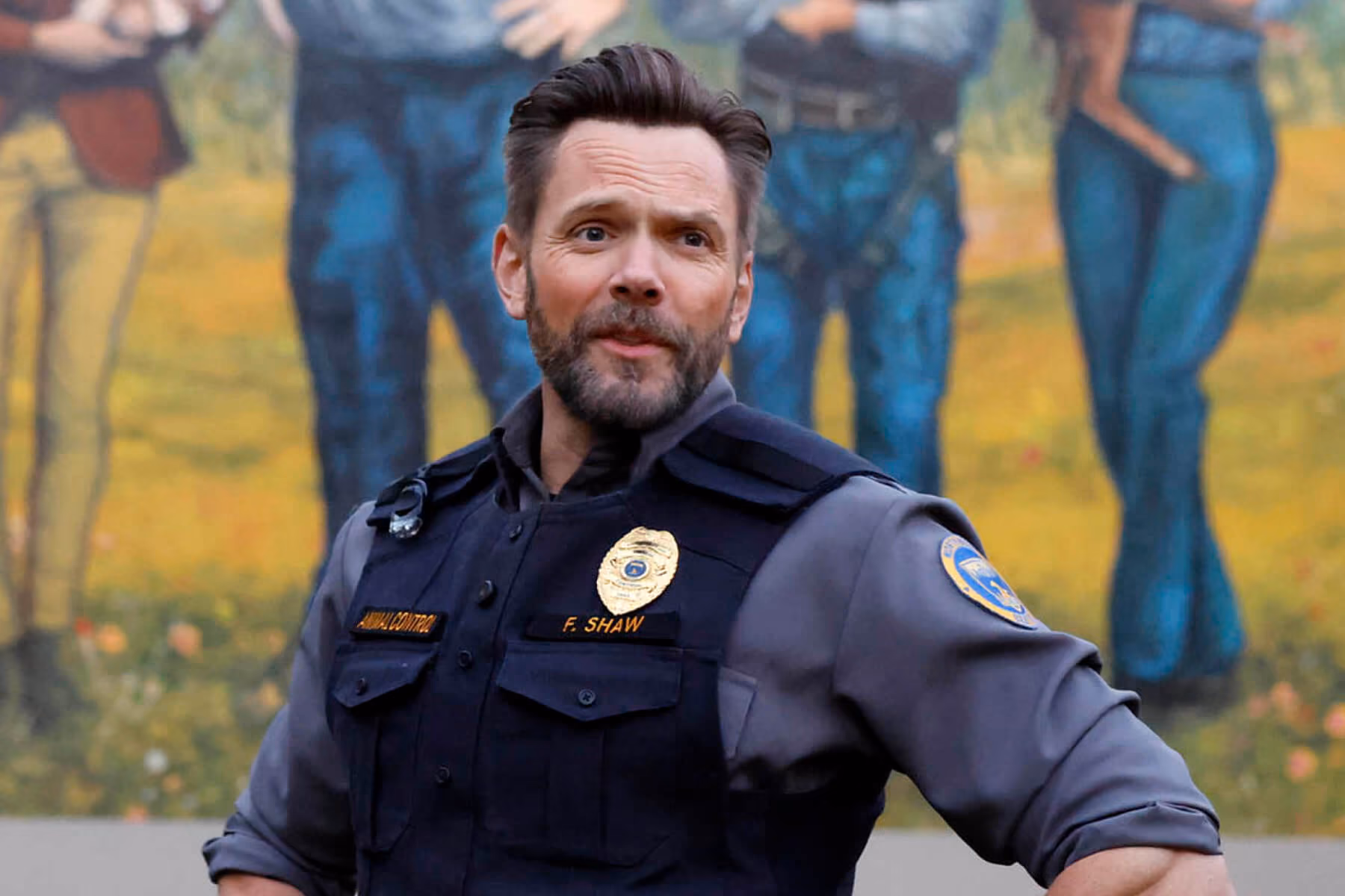 Uniformed officer stands in front of a mural