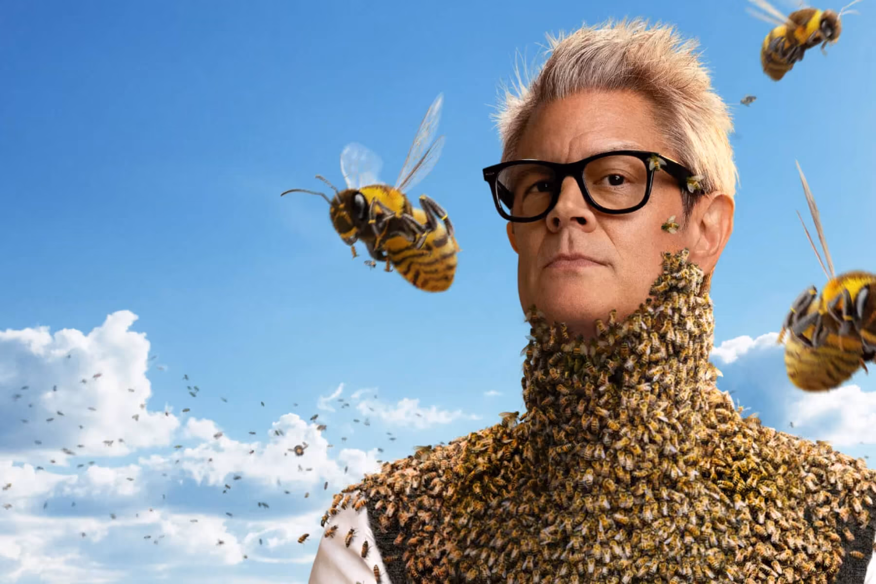 Man in glasses covered in a swarm of bees