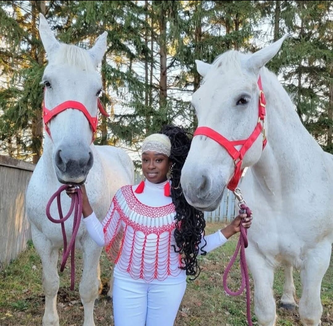 Queen Sabrina stands in between two, grey, female Percherons, coordinating with them in her red and white.