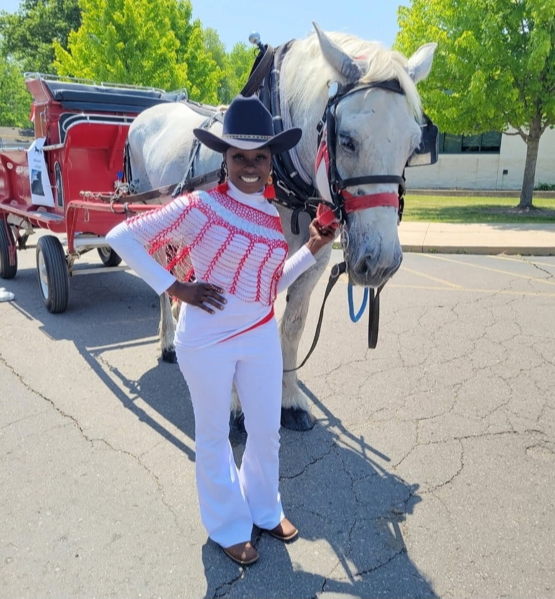 Queen Sabrina stands holding Bell who's attached to a carriage.