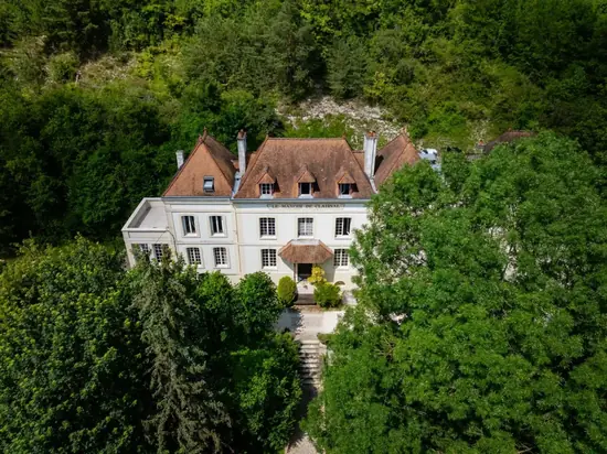 Vue aérienne du Domaine de Gaston, maison de maître blanche nichée au cœur d'une forêt verdoyante