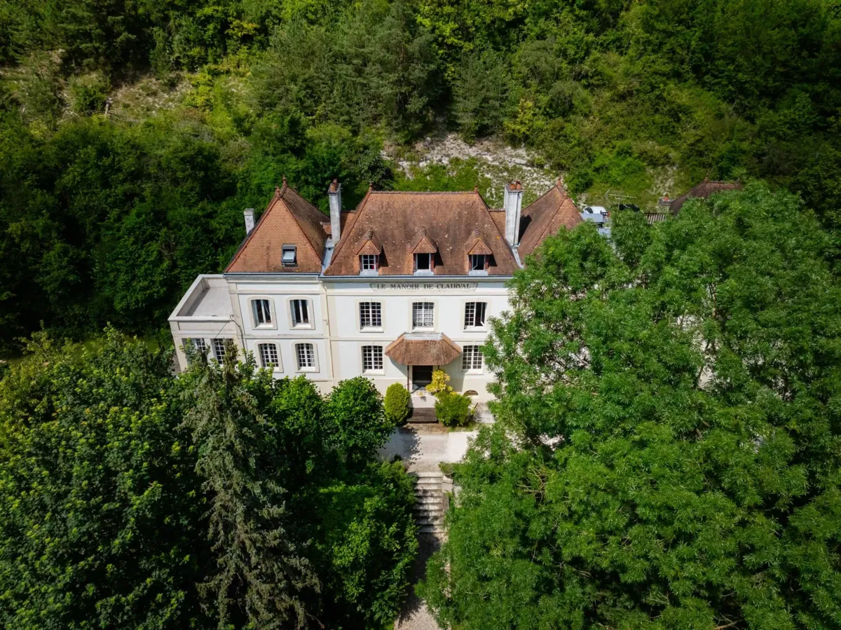 Vue aérienne du Domaine de Gaston, maison de maître blanche nichée au cœur d'une forêt verdoyante