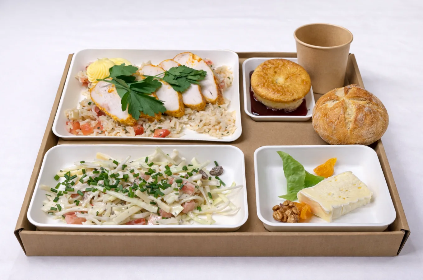 Plateau-repas complet en vue de dessus avec escalope de volaille sur lit de taboulé, salade de champignons à la crème, plateau de fromages aux fruits secs, petit pain et dessert individuel.