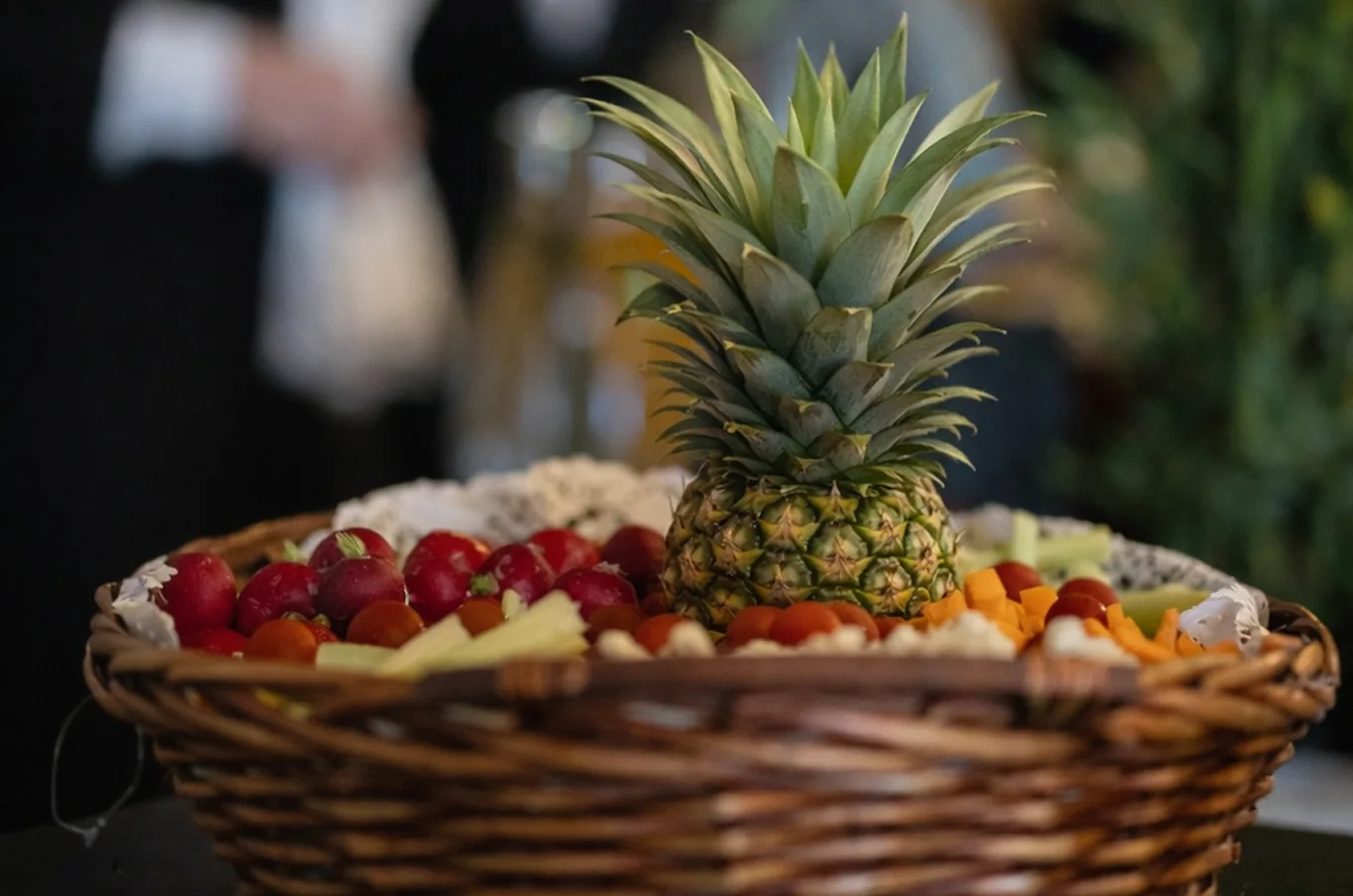 Corbeille en osier garnie de fruits frais découpés autour d'un ananas dressé en pièce centrale, présentation décorative pour buffet de réception.