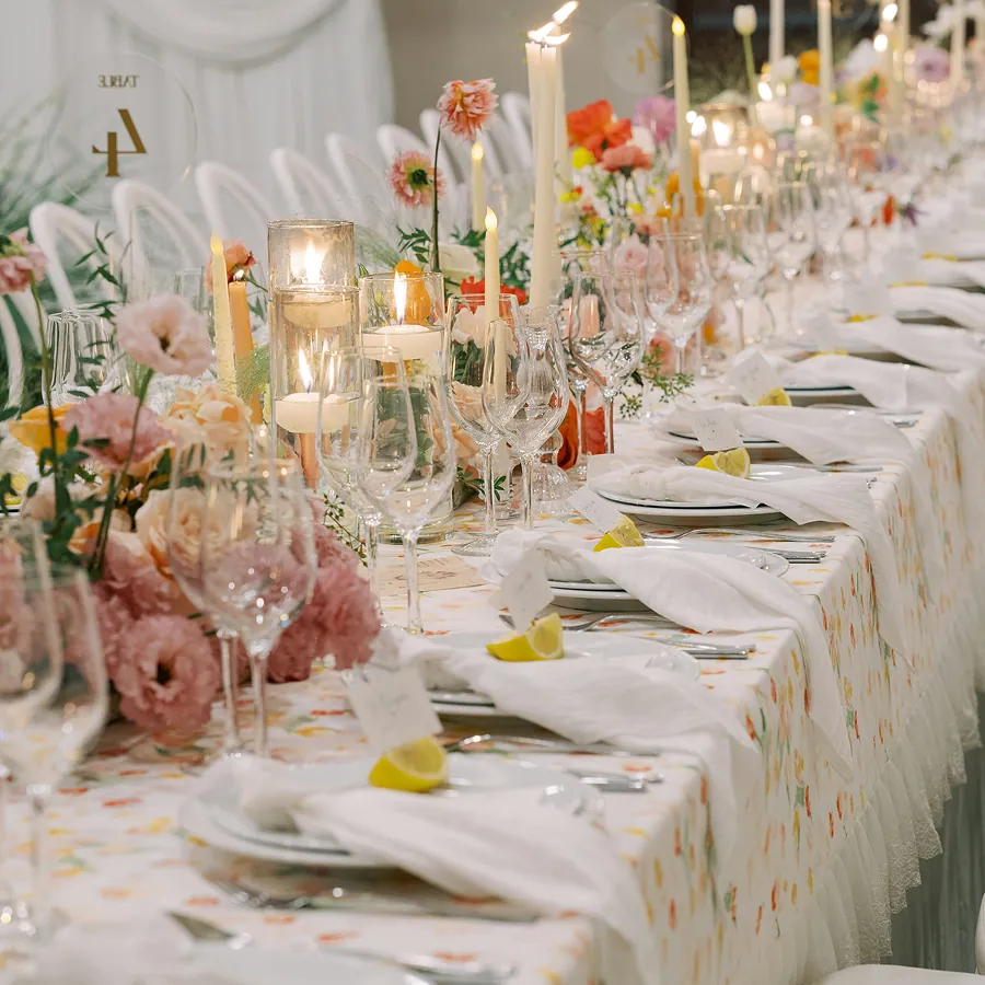 Dressage de table élégant avec assiettes en porcelaine, verres en cristal et compositions florales pastel pour réception.