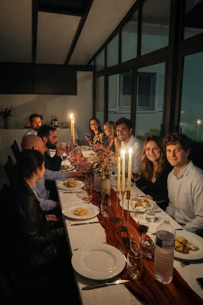 Diner d'invités attablés autour d'une longue table avec bougies allumées et chemin de table en tissu rouille — réception intimiste en véranda.