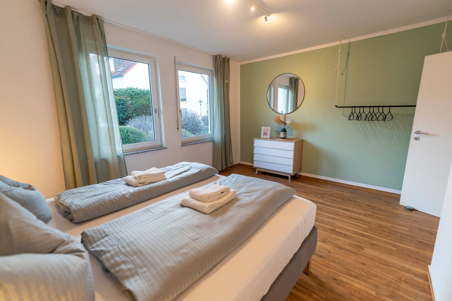 Bedroom with king-size bed, dresser and clothes hooks.