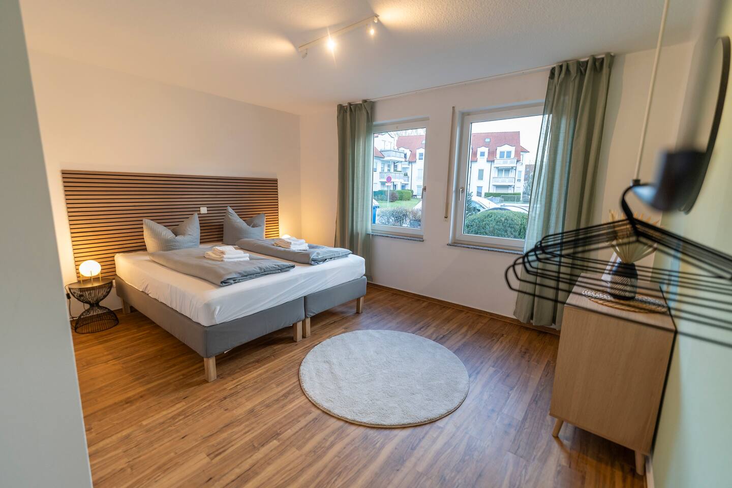Bedroom with king-size bed, dresser and clothes hooks.