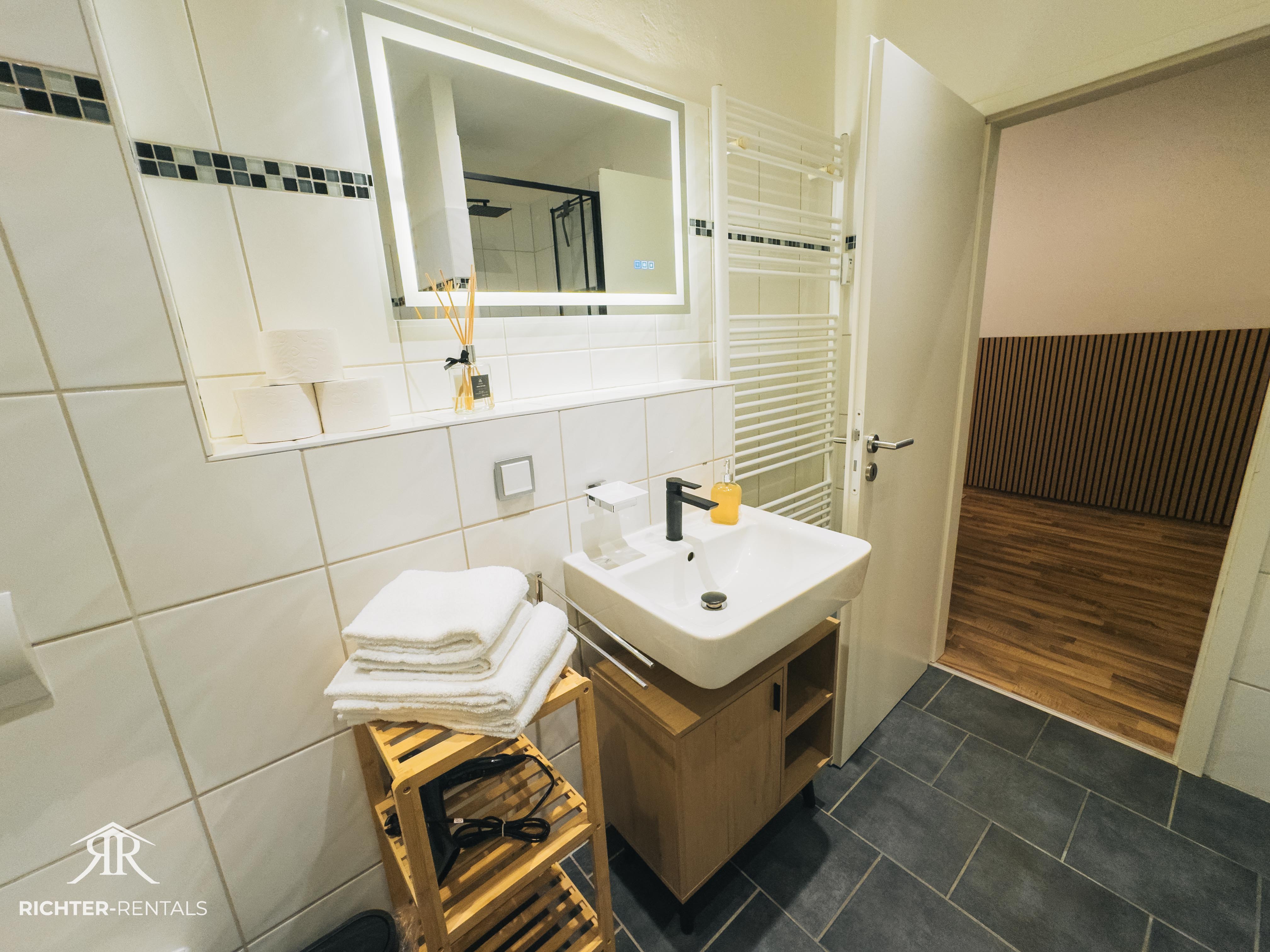 Bathroom with illuminated mirror, radiator & modern sink