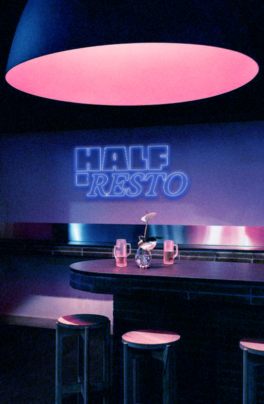 Intérieur d'un restaurant avec un comptoir, des tabourets et un éclairage rose, avec un néon au mur affichant 'HALF RESTO'.