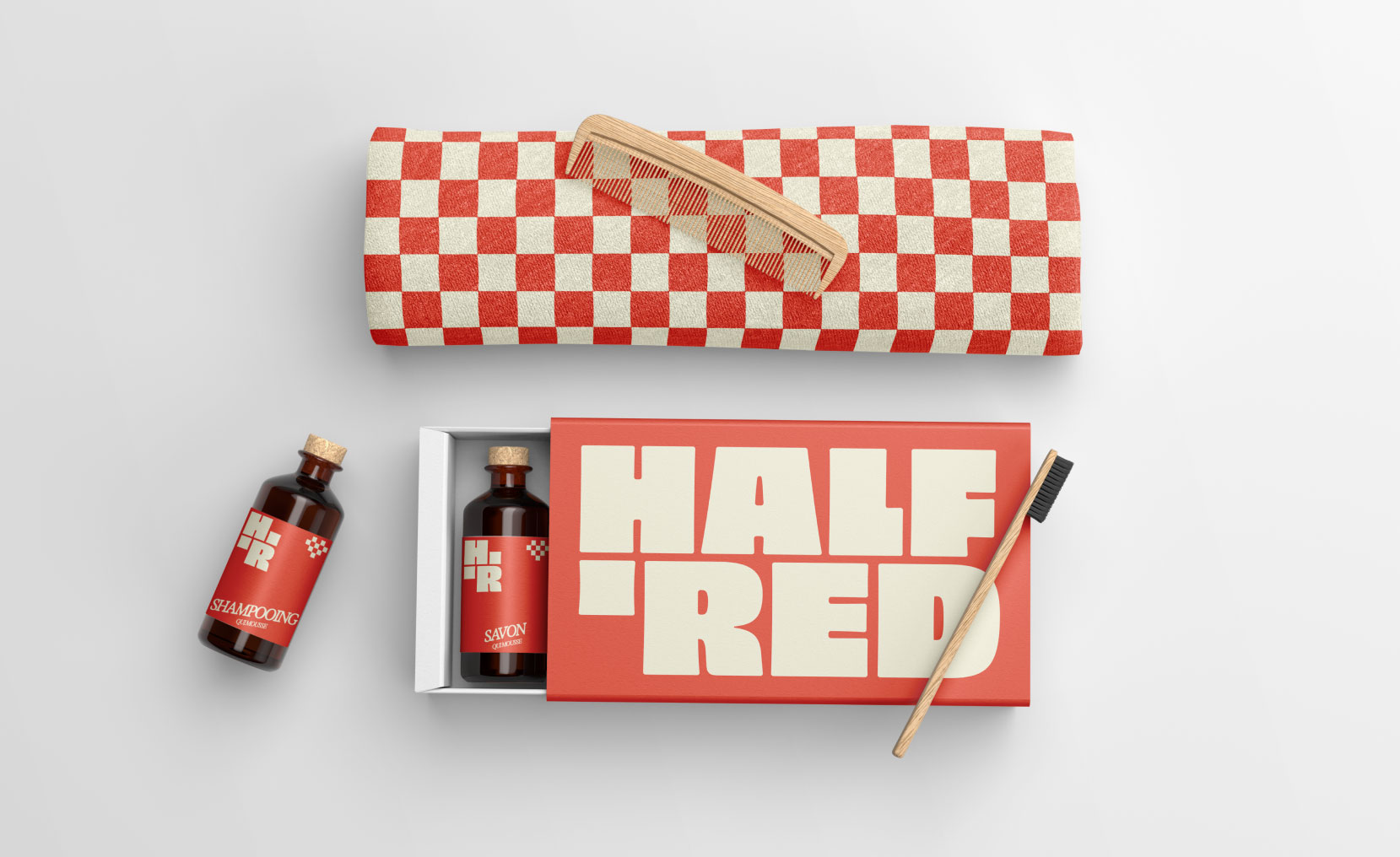 Coffret de produits de toilette Half 'Red comprenant une serviette à carreaux rouges et blancs, un peigne en bois, deux flacons avec bouchons en liège étiquetés shampooing et savon, et une brosse à dents en bois.