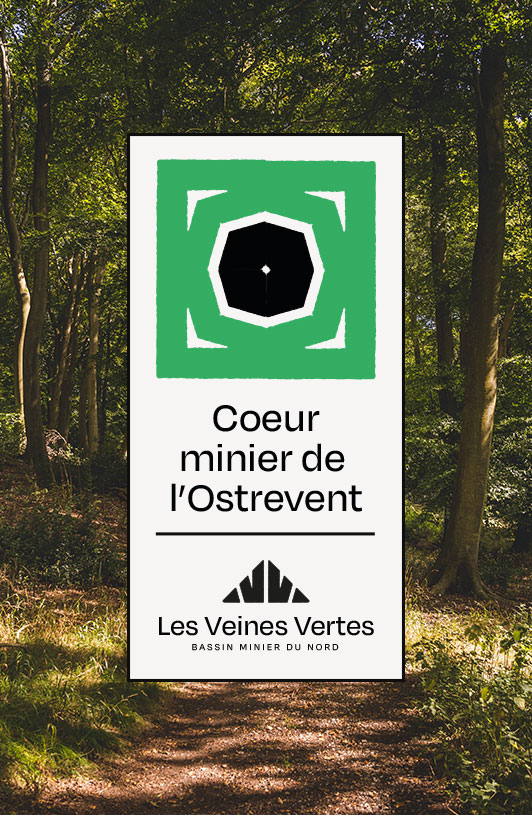 Panneau avec logo vert et noir affichant « Coeur minier de l’Ostrevent » dans une forêt éclairée par le soleil.