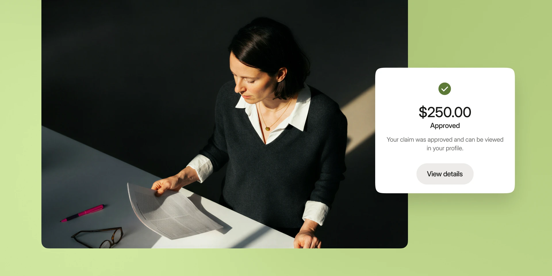 Woman in dark sweater reading paper at desk with $250.00 claim approval notification on screen.