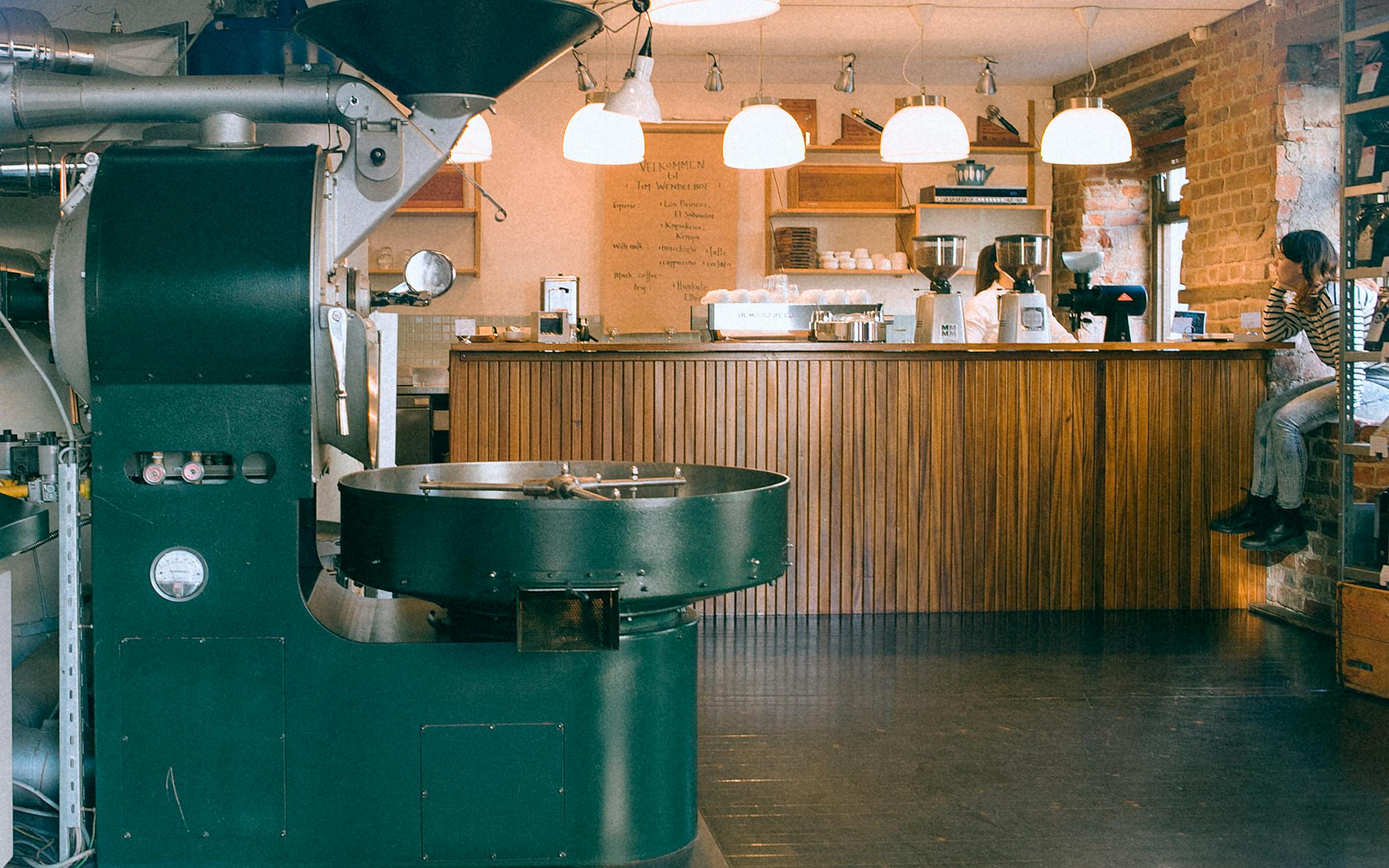 Coffee roasting equipment lit by overhead lamps in a quiet roastery