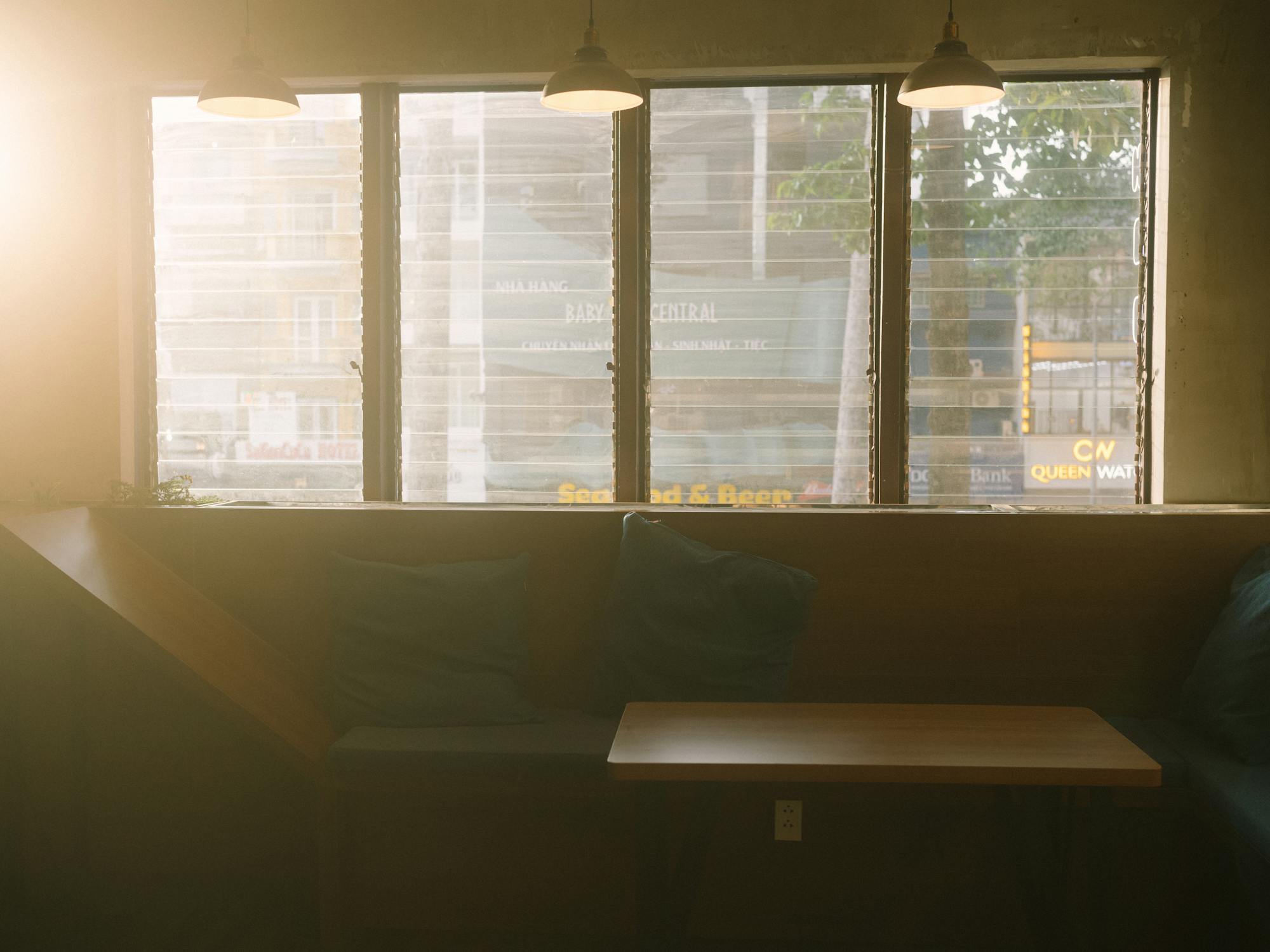 Warm sunlit cafe interior with pillows and tables by the window