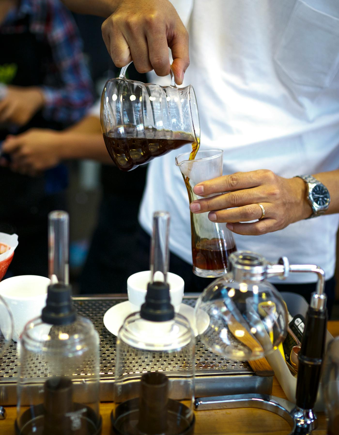 Barista pouring brewed coffee into a clear glass