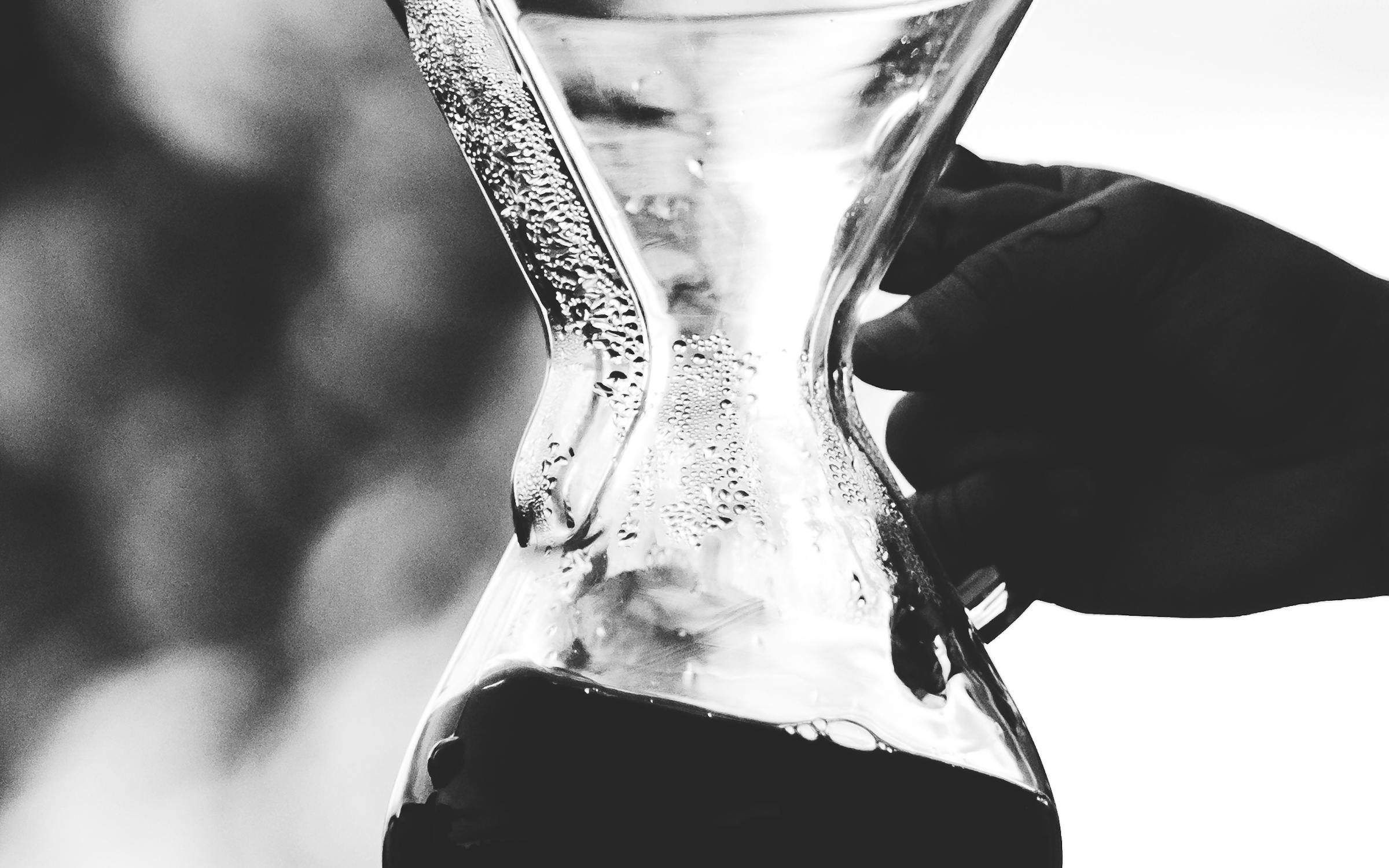 Silhouette of hands pouring water from a kettle into a Chemex brewer