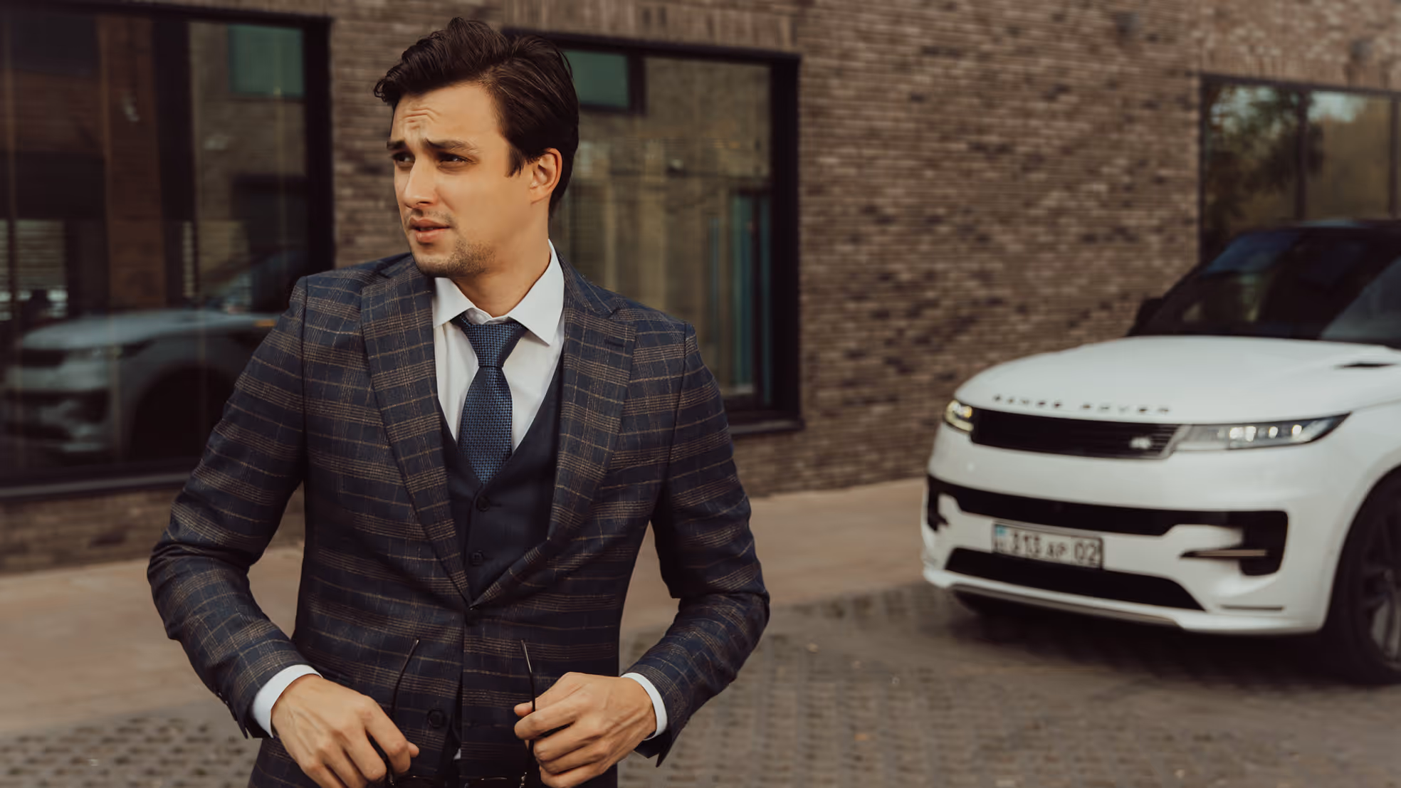Элегантный мужчина в костюме перед Land Rover Sport