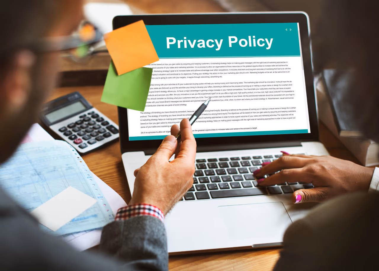 Two people reviewing a laptop screen displaying a privacy policy document with sticky notes attached.
