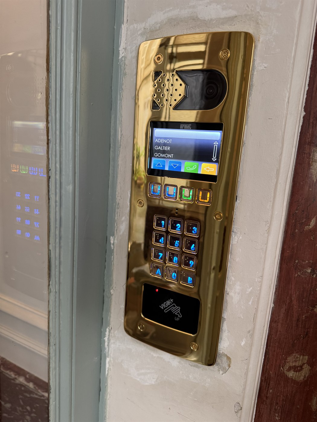Platine d’interphone Urmet dorée avec caméra, écran, clavier codé et lecteur VIGIK+, dans un immeuble parisien
