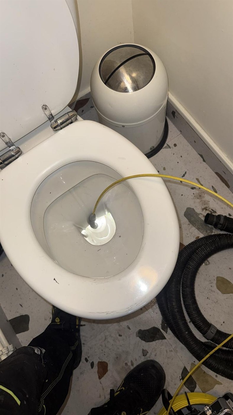 Débouchage d’un WC : passage du furet dans la cuvette, aspirateur de chantier en attente