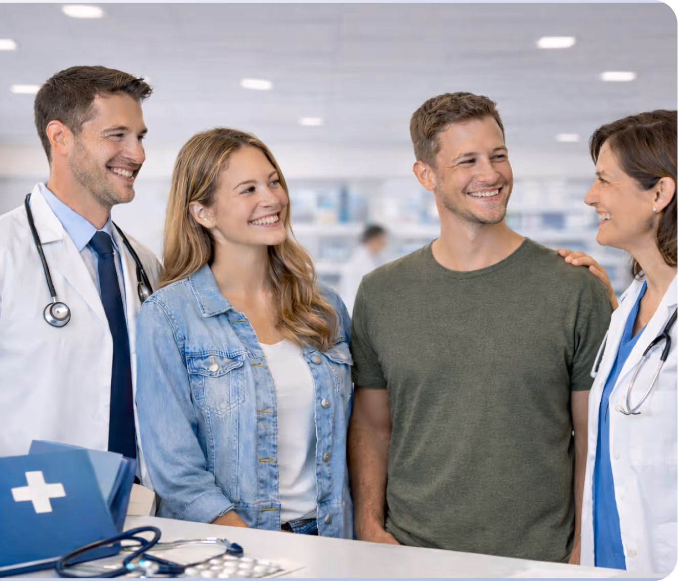 Two doctors smiling and talking with a happy couple in a bright medical office.