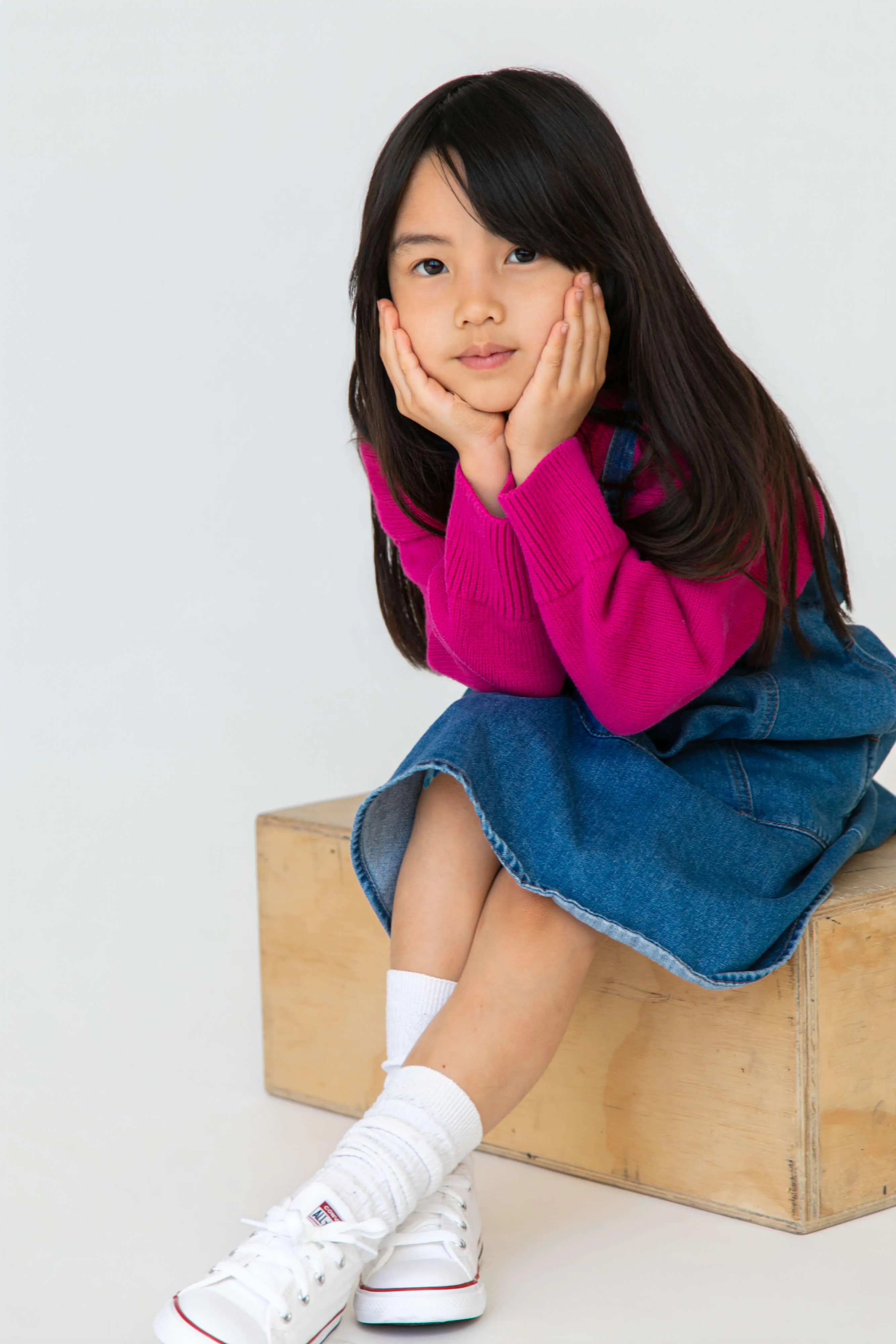 A little girl sitting on top of a wooden box.