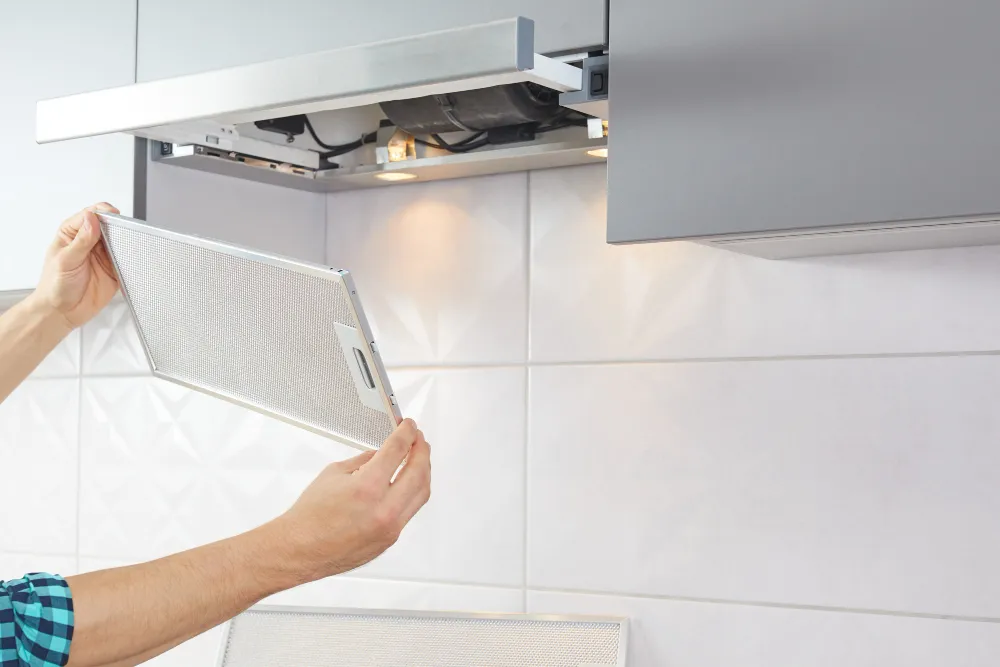 Range hood grease filter being removed for cleaning or replacement`