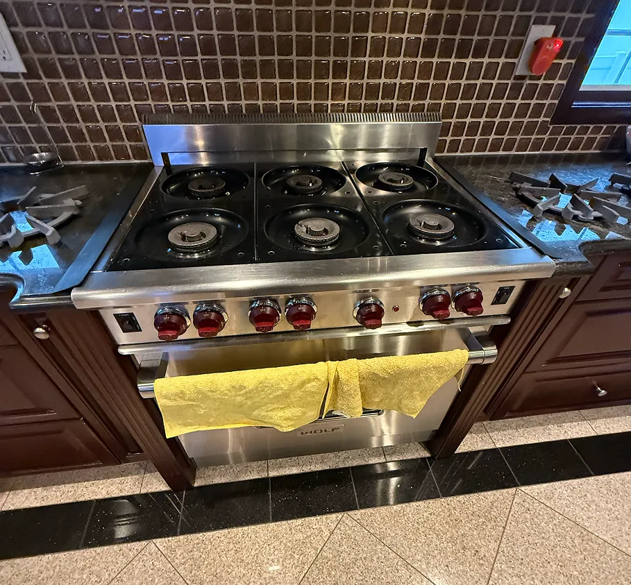 Wolf 6-burner gas range with griddle being serviced in a residential kitchen