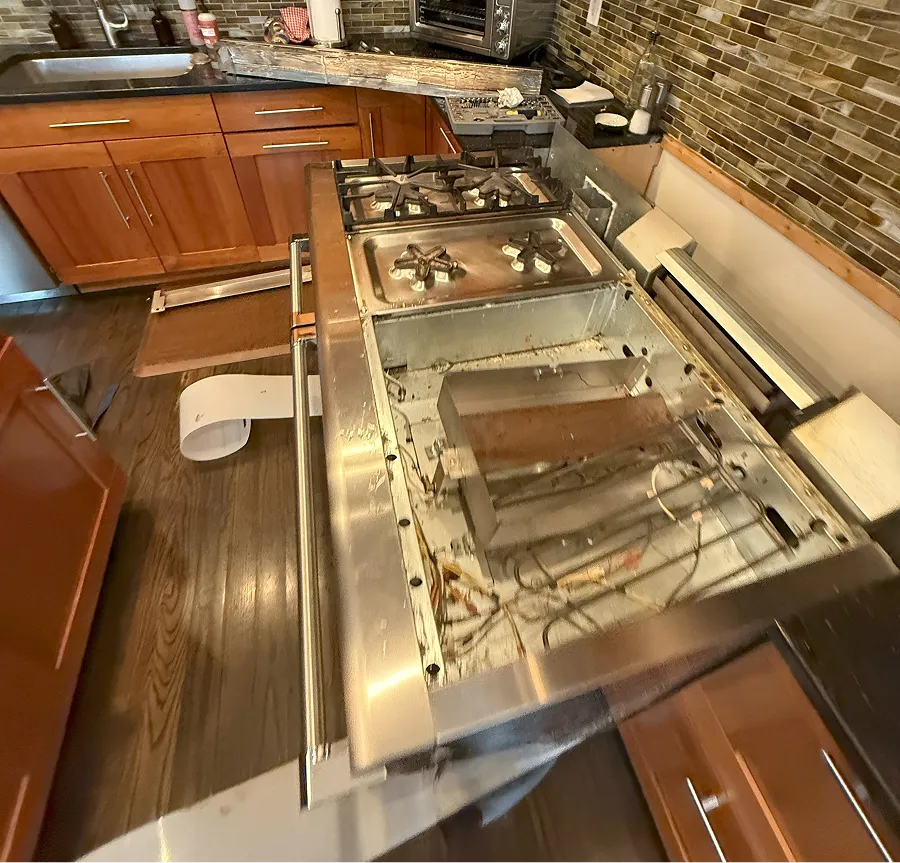 Gas range disassembled with burner components exposed during a stove repair service call in NJ