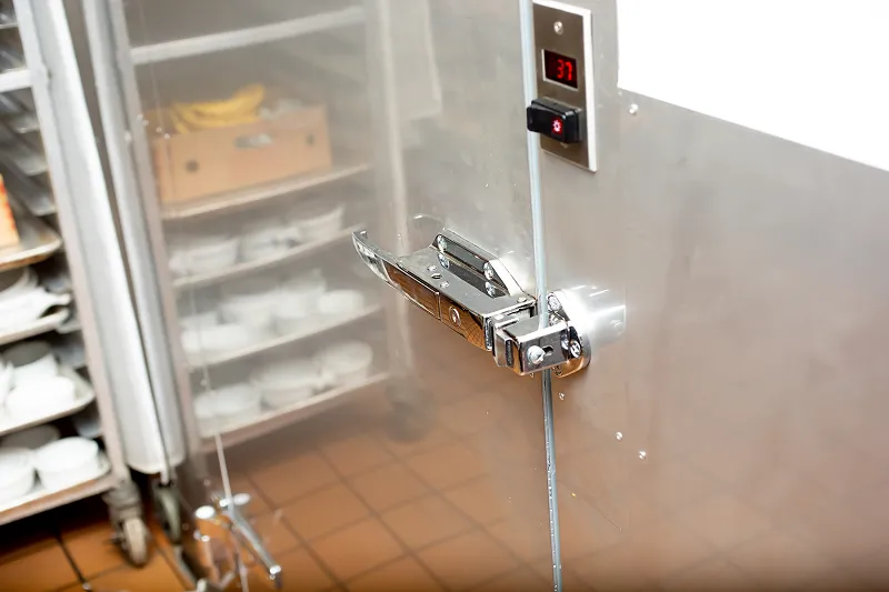 Walk-in refrigerator door latch and temperature control panel showing 37°F in a commercial kitchen