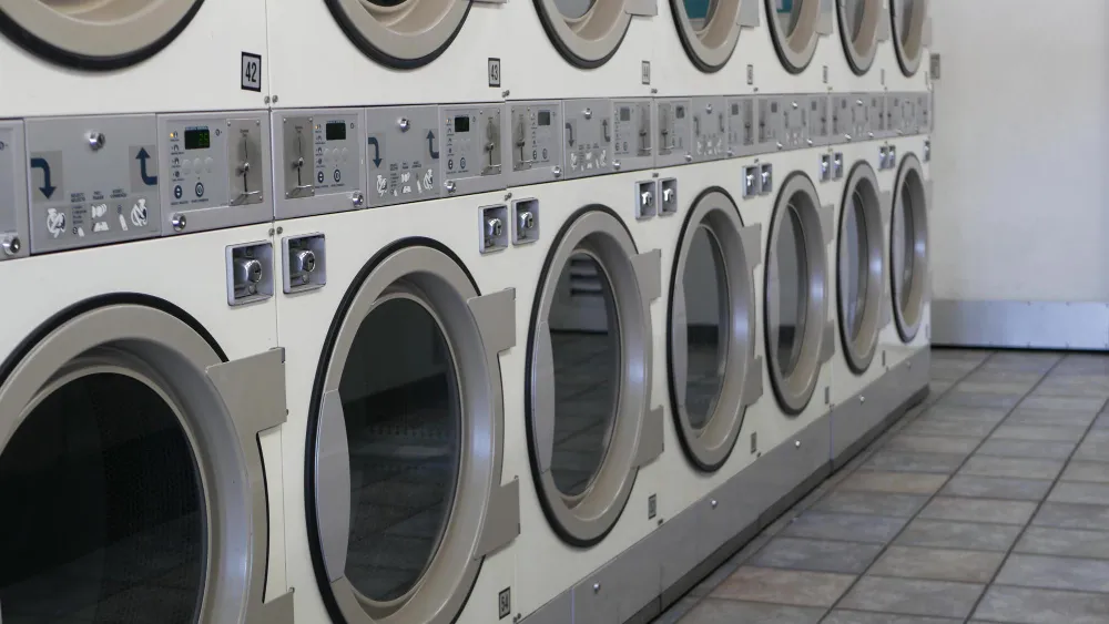 Row of commercial front-load washers in a laundromat