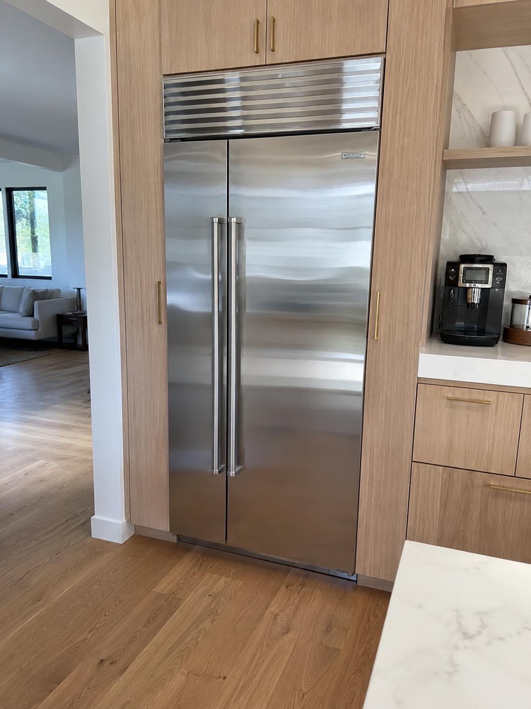 Stainless steel Sub-Zero refrigerator with French doors and bottom freezer in a modern wood kitchen