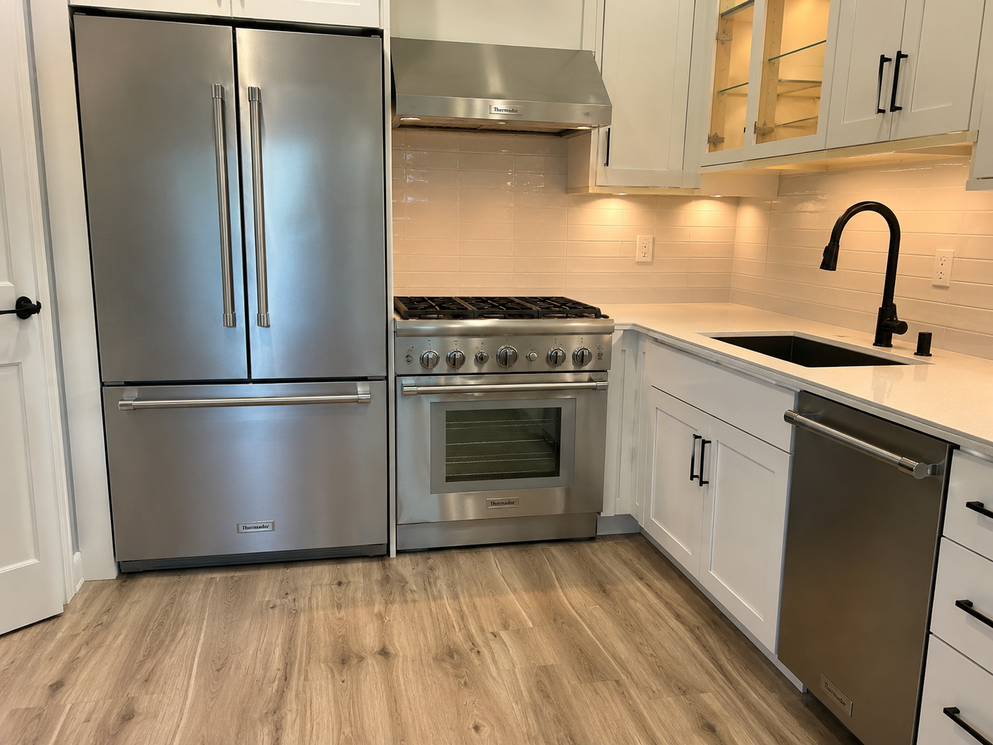 Stainless steel Thermador French-door refrigerator and range in a bright white kitchen