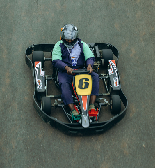 Person wearing helmet driving go-kart number 6 on a race track.
