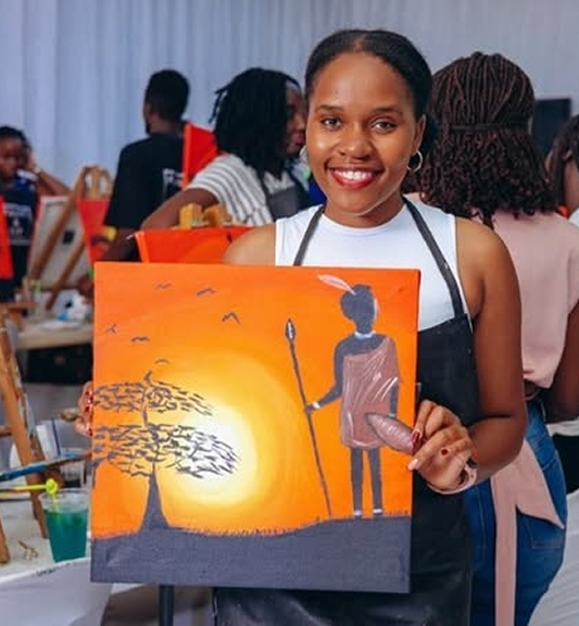 A smiling woman holding a painting of a silhouette with a spear and a tree against an orange sunset background.