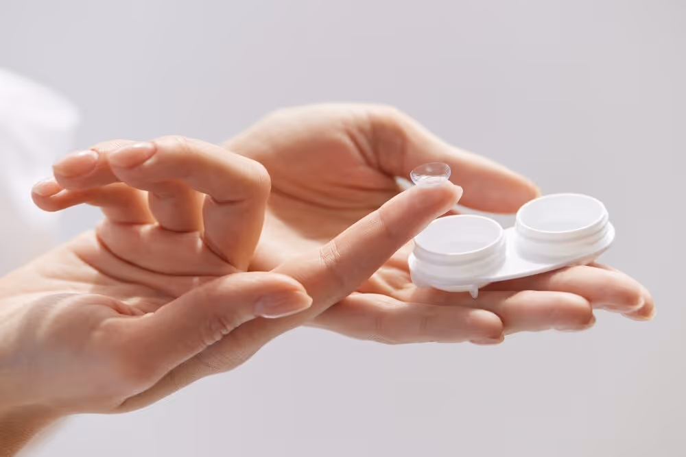Hands holding contact lenses.