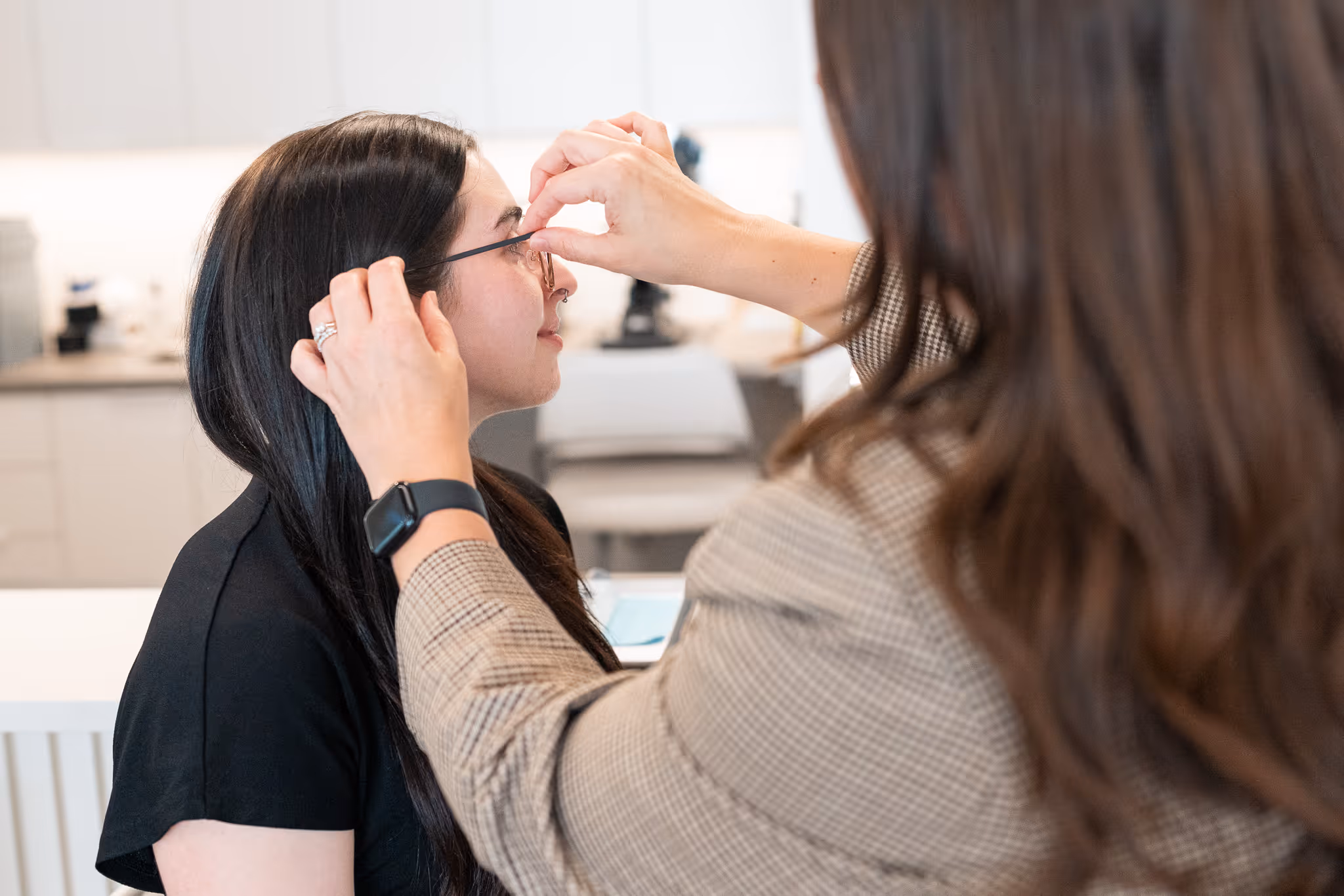 Person adjusting glasses for person trying them on