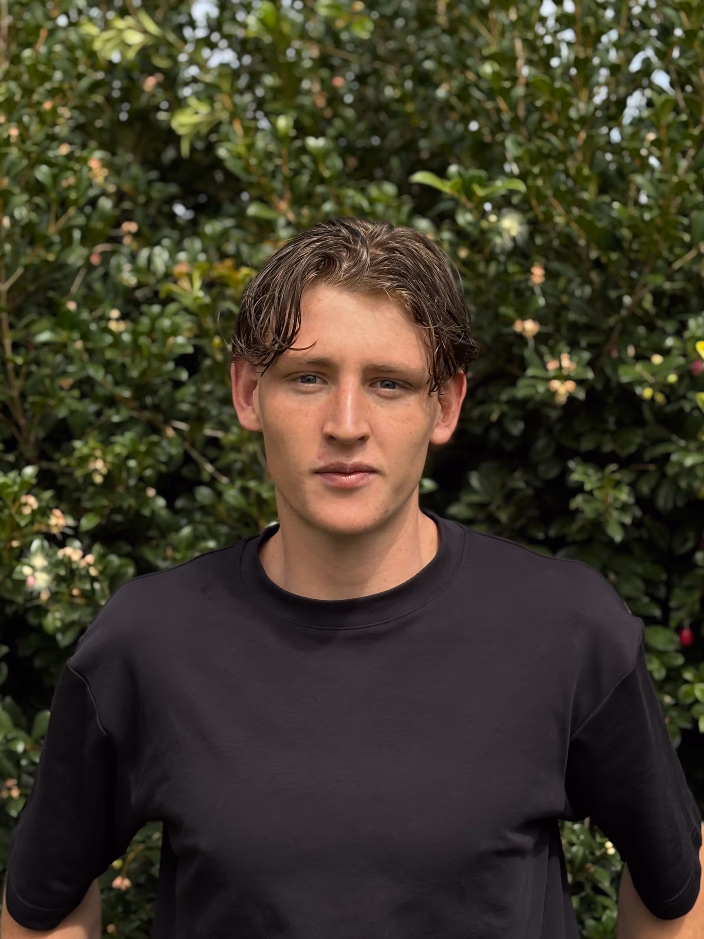 Oak Jardi Tupman, founder of Jardi Digital Perth web design agency, wearing black t-shirt with green garden foliage background