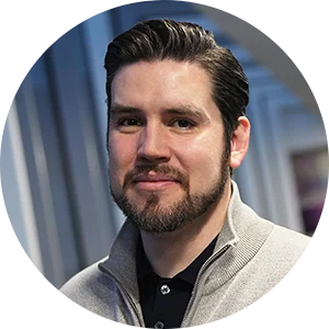 Brand expert Paul with dark hair and beard wearing a light gray zippered sweater over a black polo shirt.