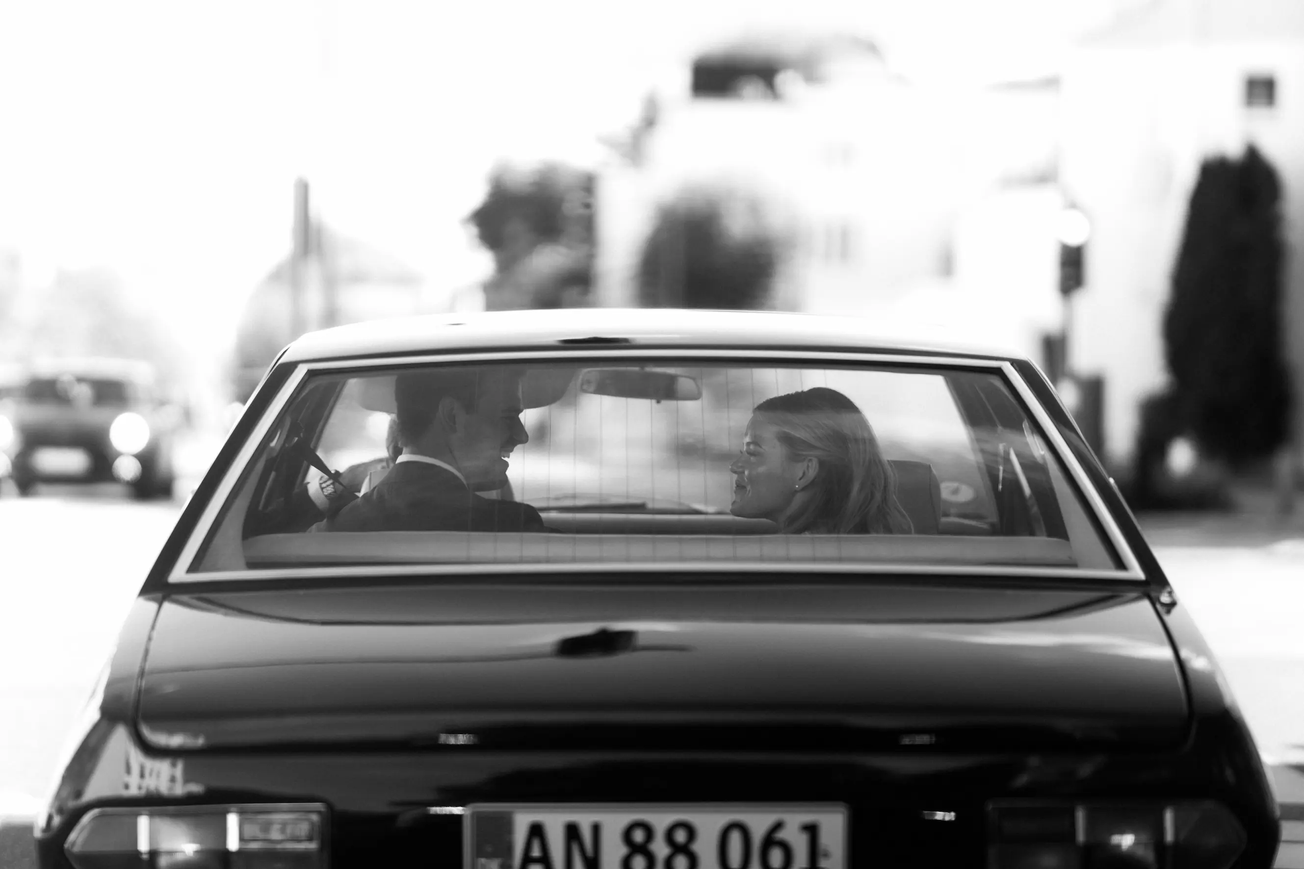 A black and white image of a bride and groom sitting in a car.