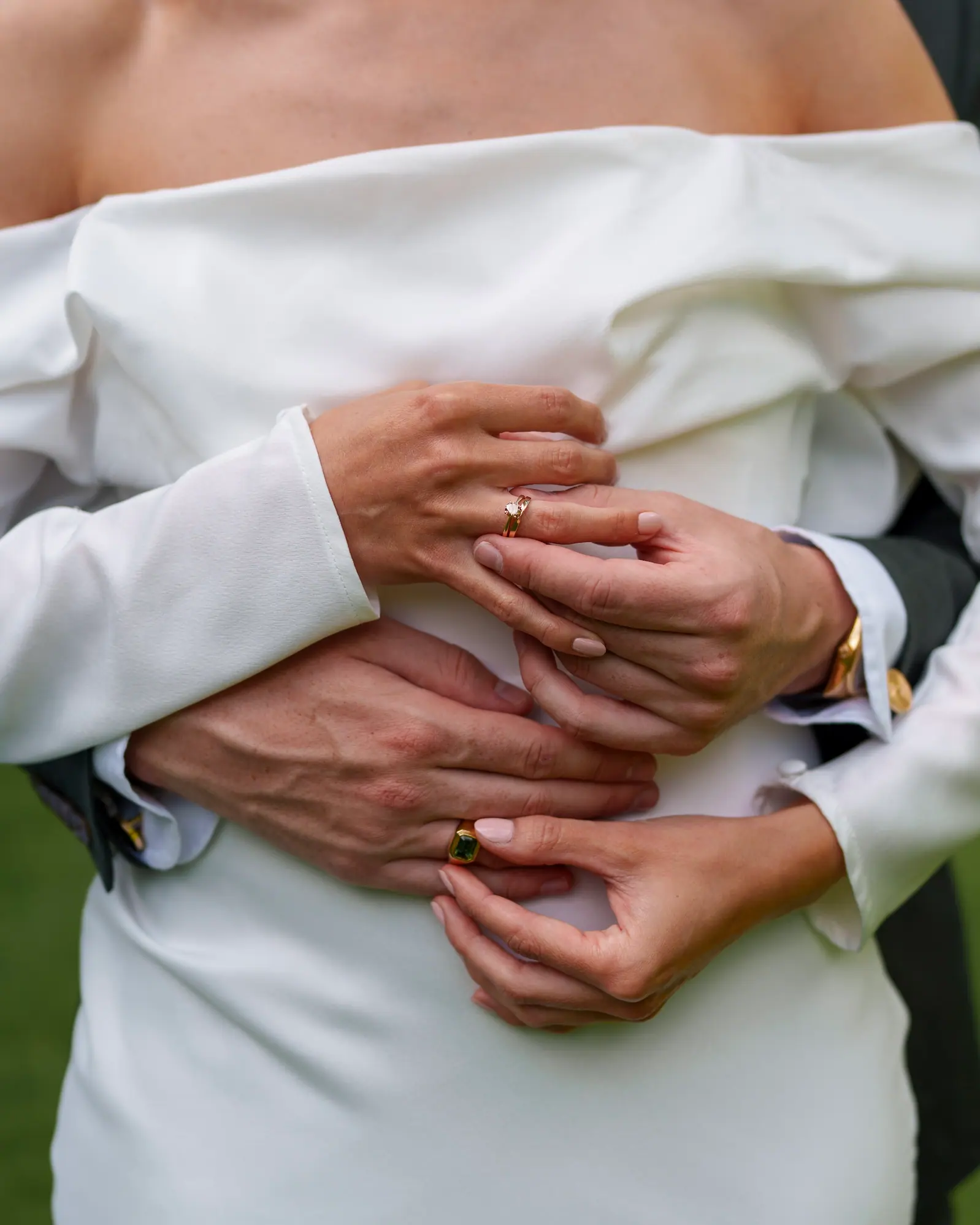 A detail of a bride and groom embraced with their wedding rings.