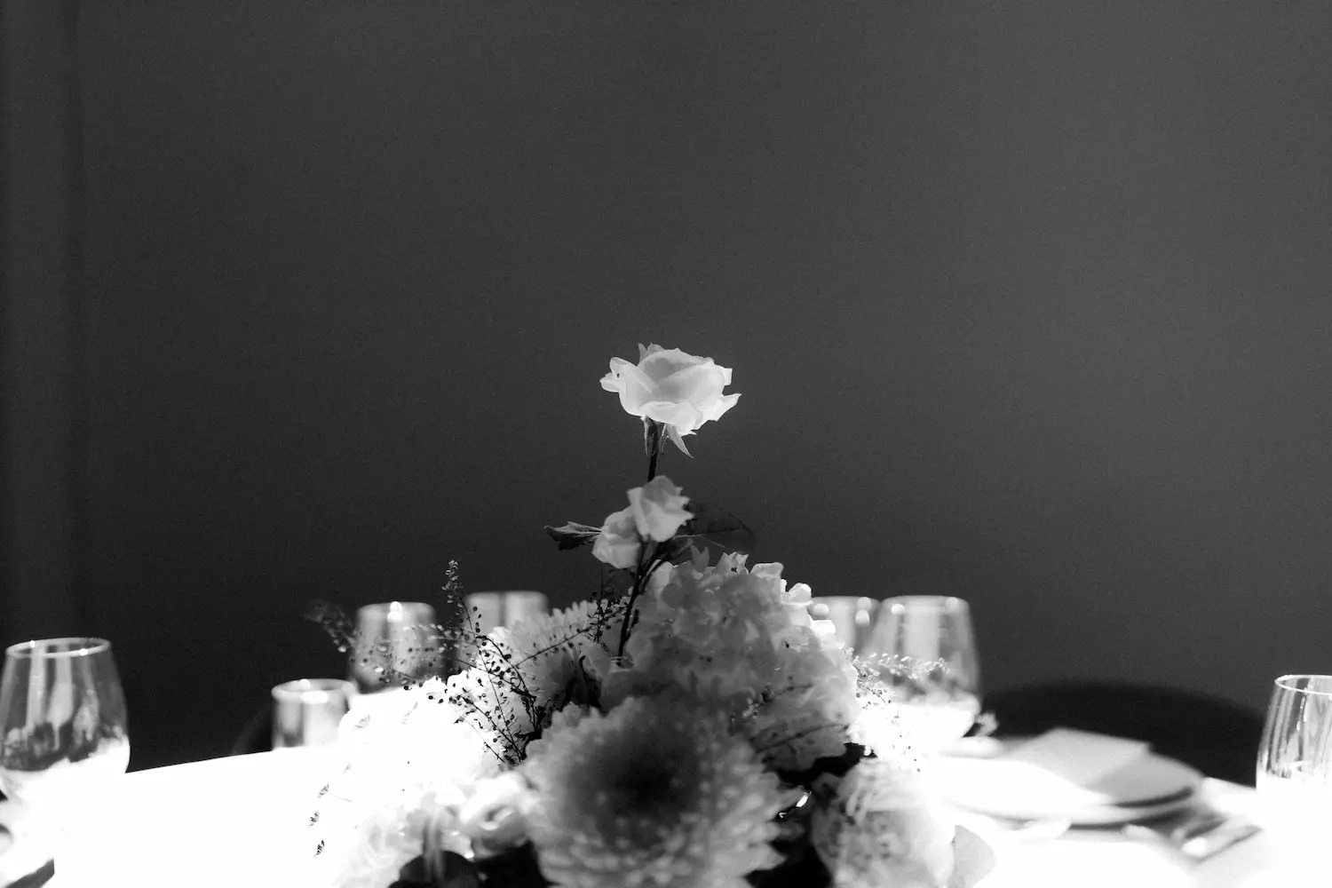 A black and white image of a flower at a wedding reception table