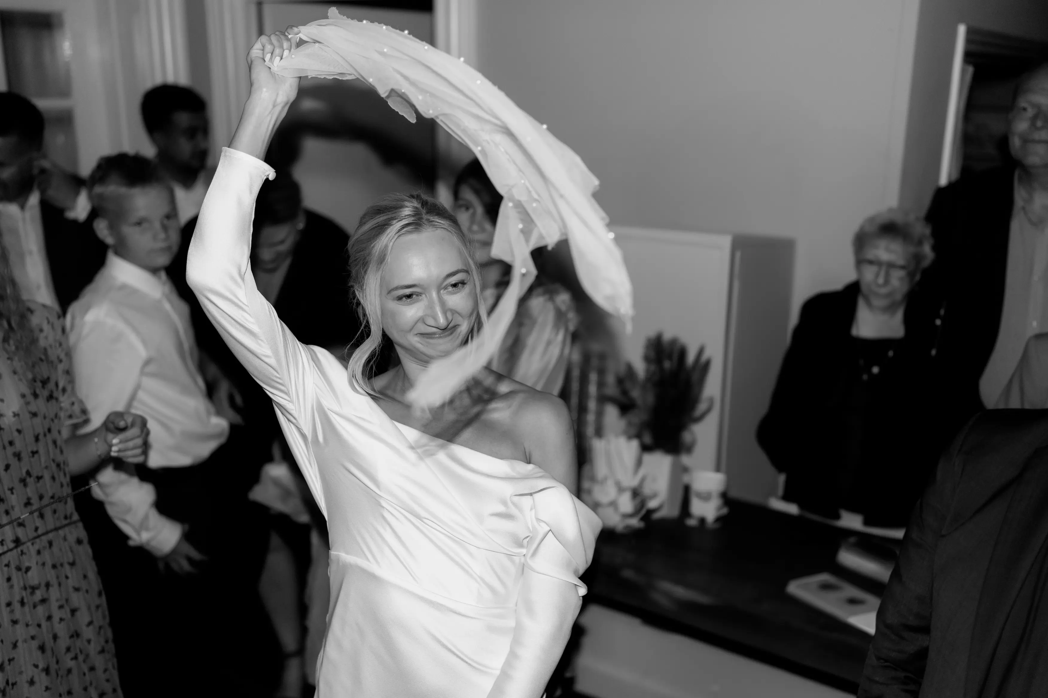 A black and white photographer of a bride dancing at her wedding.
