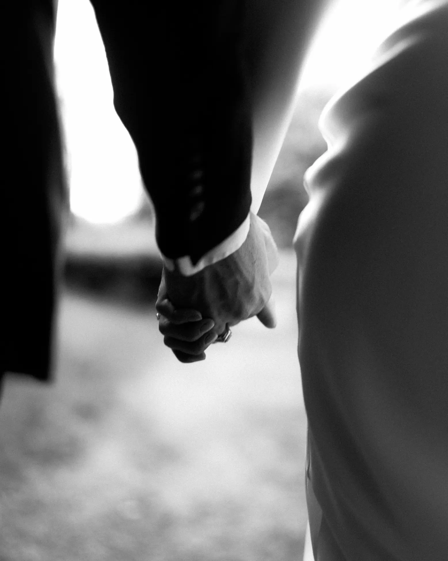 Bride and groom holding hands, walking along a street