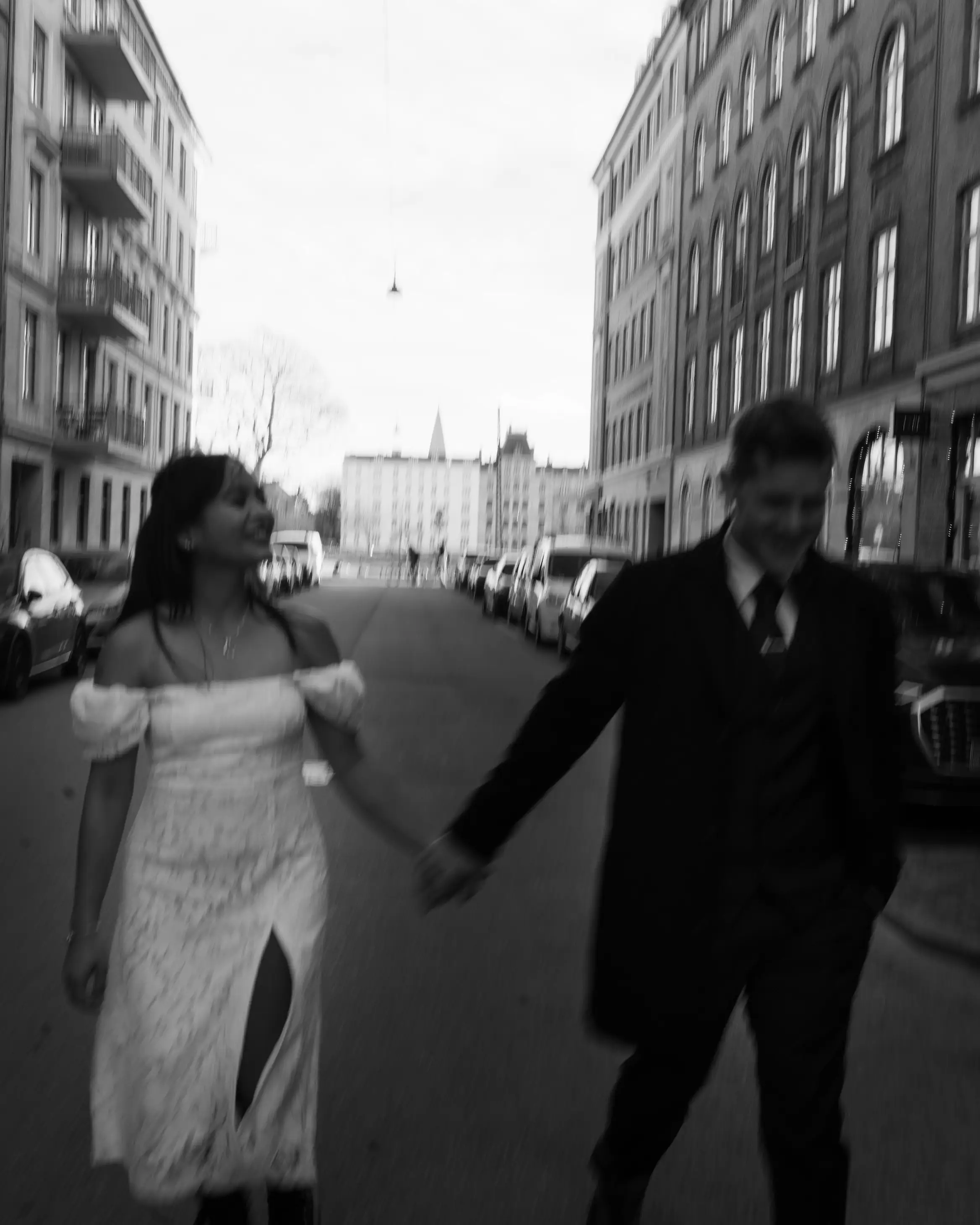 Bride and groom holding hands and walking through street